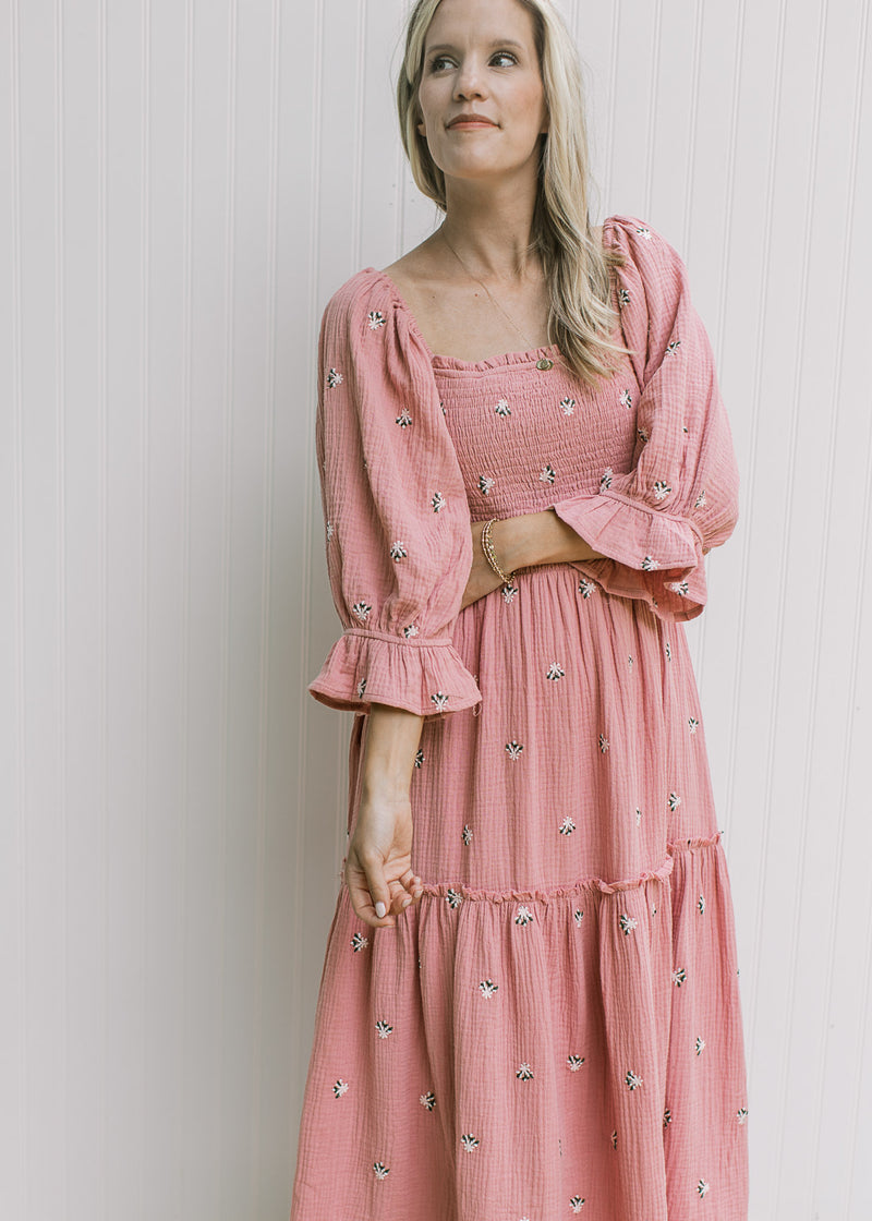 Model wearing a rose dress with pink flowers, poet sleeves and a smocked bodice. 