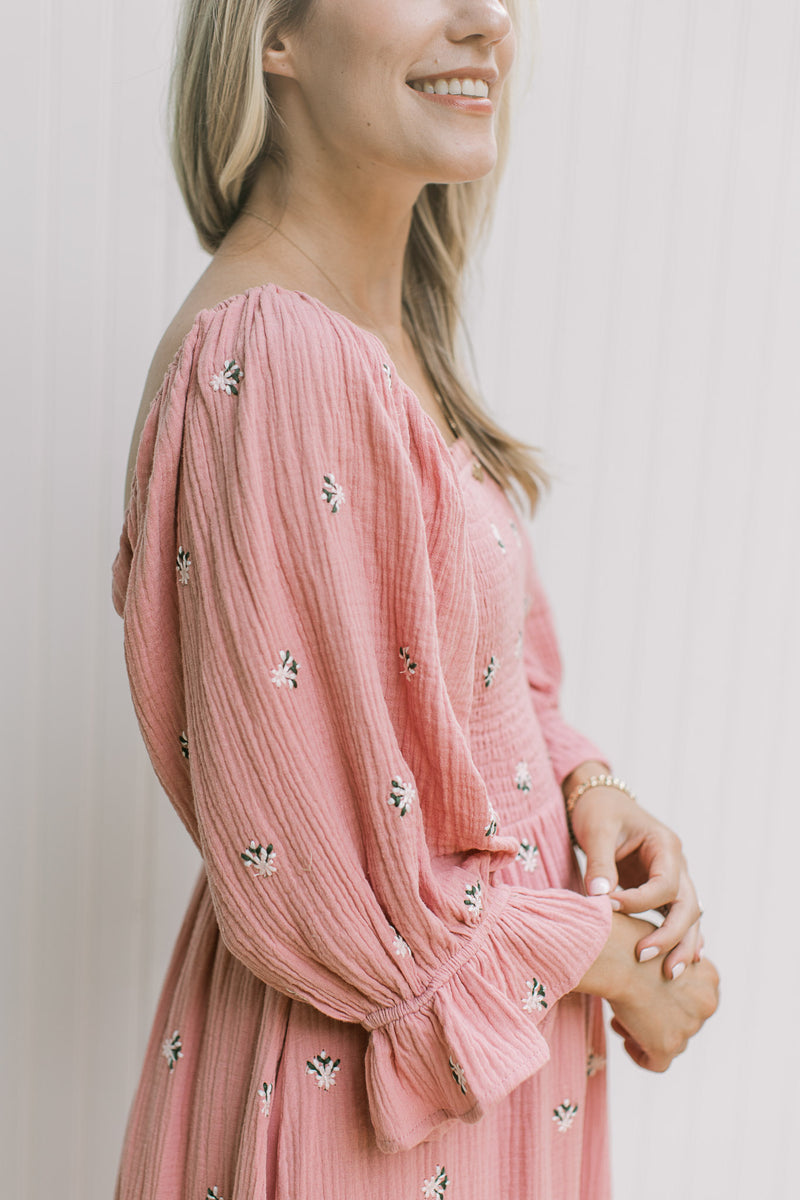 Close up of poet sleeve on a rose dress with pink flowers, a square neck and gauze material.  