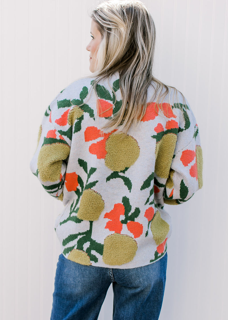 Back view of Model wearing a baby blue sweater with bright floral a mock neck and long sleeves.