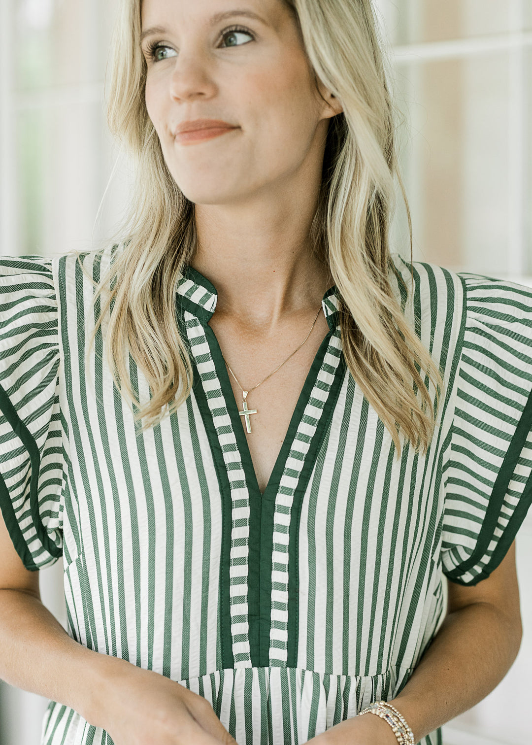 Close up of v-neck and layered flutter cap sleeves on a cream mid with green stripes. 