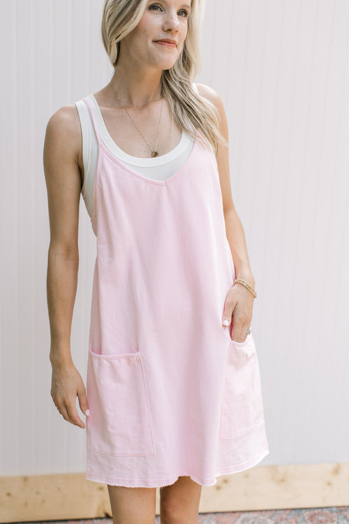 Model wearing a fully lined pink romper with adjustable straps and front patch pockets.