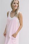 Model wearing a white top under a pink romper with adjustable straps and front patch pockets.