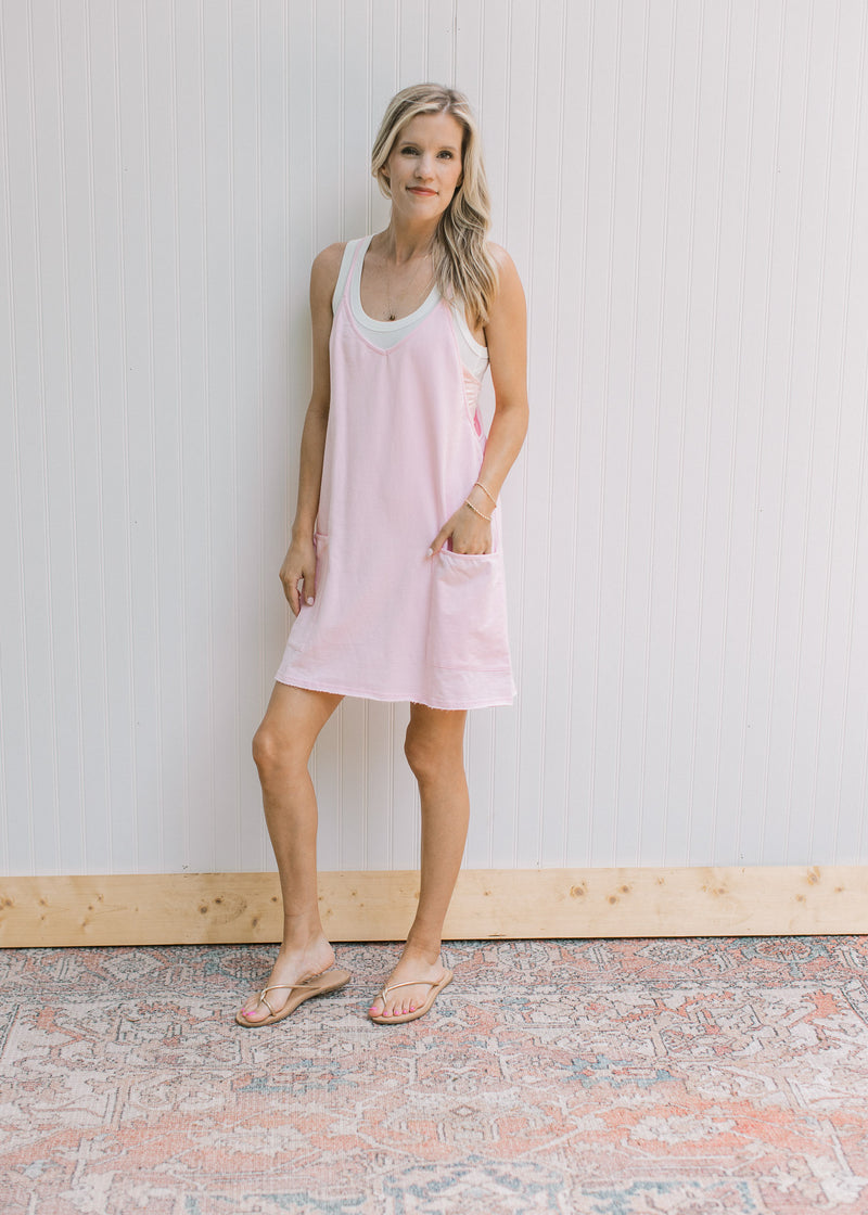 Model wearing sandals with a fully lined pink romper with adjustable straps and front patch pockets.