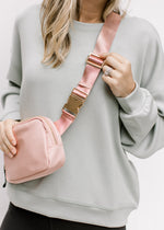 Model in a sage top with a pink crossbody belt bag with adjustable strap, two pockets and gold clasp