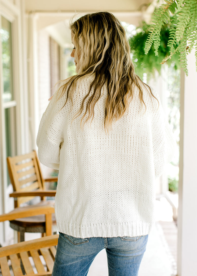 Back view of model wearing a cream yarn cardigan with long sleeves. 