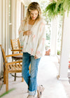 Model wearing jeans with a cream yarn cardigan ordained with pink crochet bows. 