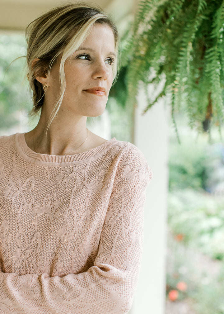 Close up of floral pattern on a loose knit sweater with a round neck and long sleeves.