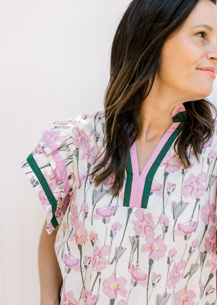 Model wearing a cream top with pink and green floral and pink and hunter trim at neck and sleeve.