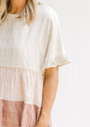 Close up view of ruffle on short sleeve of a cream, light pink and mauve colorblock top.