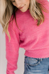 Model wearing a pink sweater with a slightly cropped fit and ribbed detail at neck, cuff and hem.