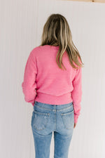 Back view of Model wearing a pink fuzzy sweater with a cropped fit, long sleeves and a round neck.