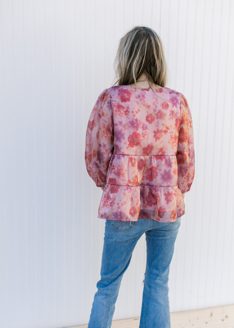 Back view of Model wearing a pink top with a floral pattern, square neck and sheer 3/4 sleeves.