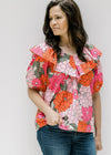 Model wearing a pink floral print top with short bubble sleeves and an elastic boat neck with ruffle