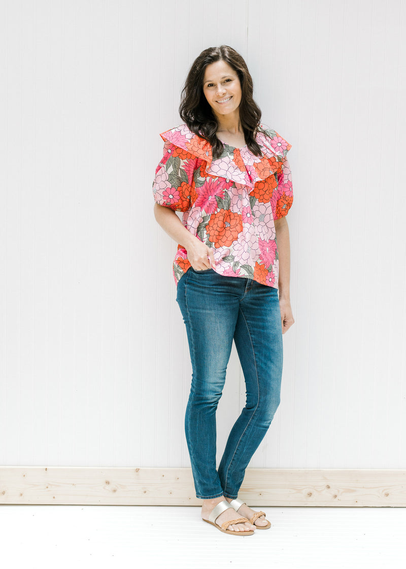 Model wearing jeans, sandals and a pink floral top with bubble short sleeves and a boat neck. 