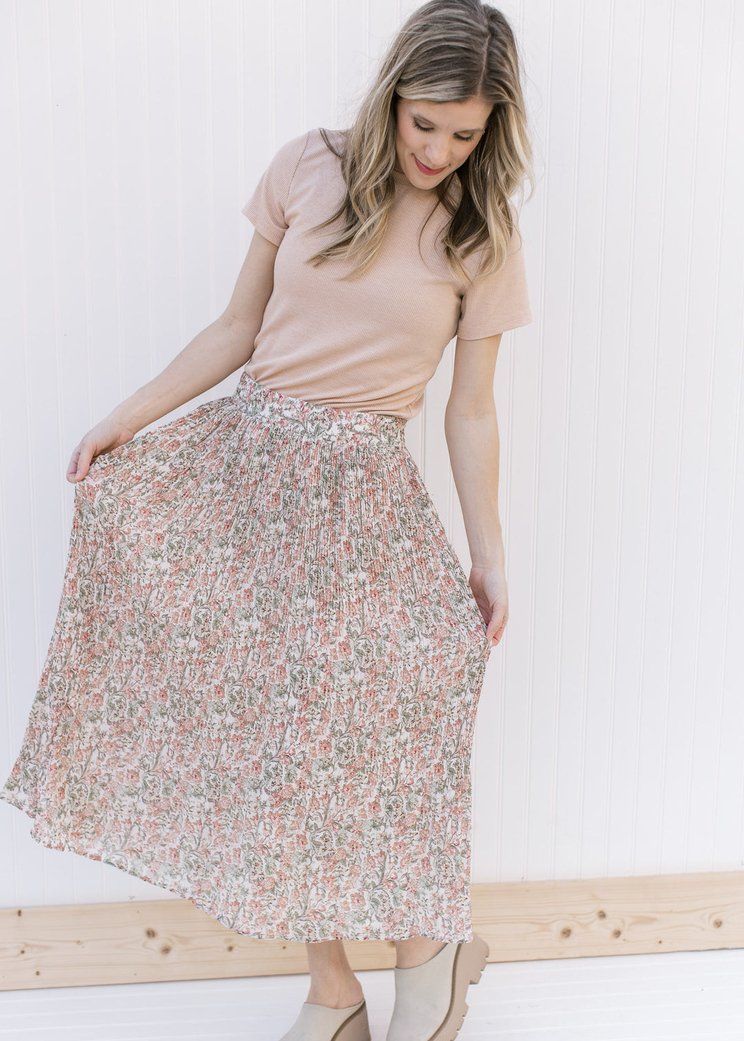 Model wearing a cream midi with pink, pale yellow and green floral and an elastic waist. 