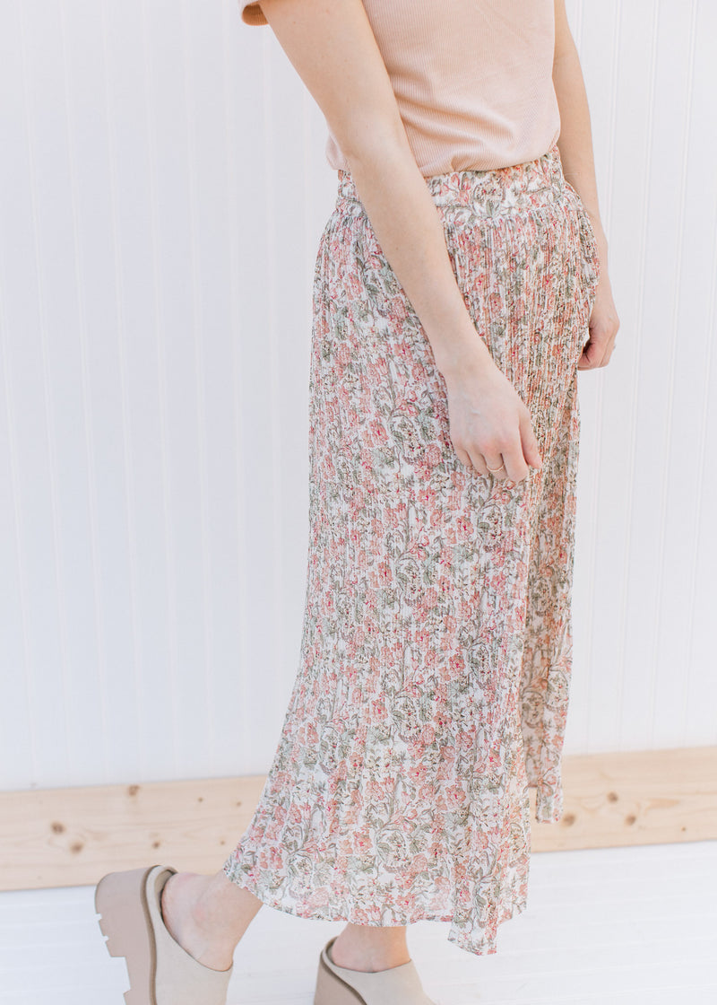 Model wearing a pleated floral midi with an elastic waistband and a polyester material.