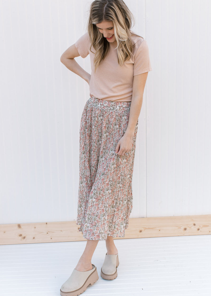 Model wearing an oatmeal top, mules and a pleated floral midi with an elastic waistband.
