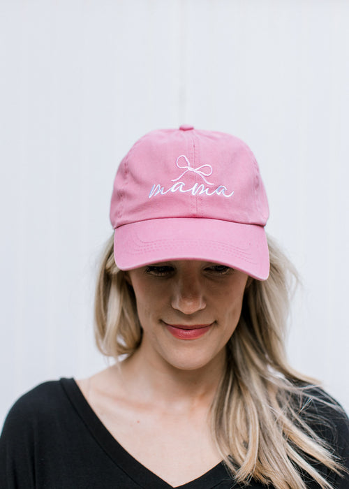 Model wearing an pink adjustable size hat with embroidered script mama with a pink bow.