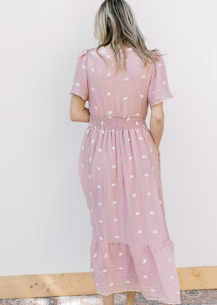 Back view of a model wearing a pink gauze midi with short sleeves and smocked waist.