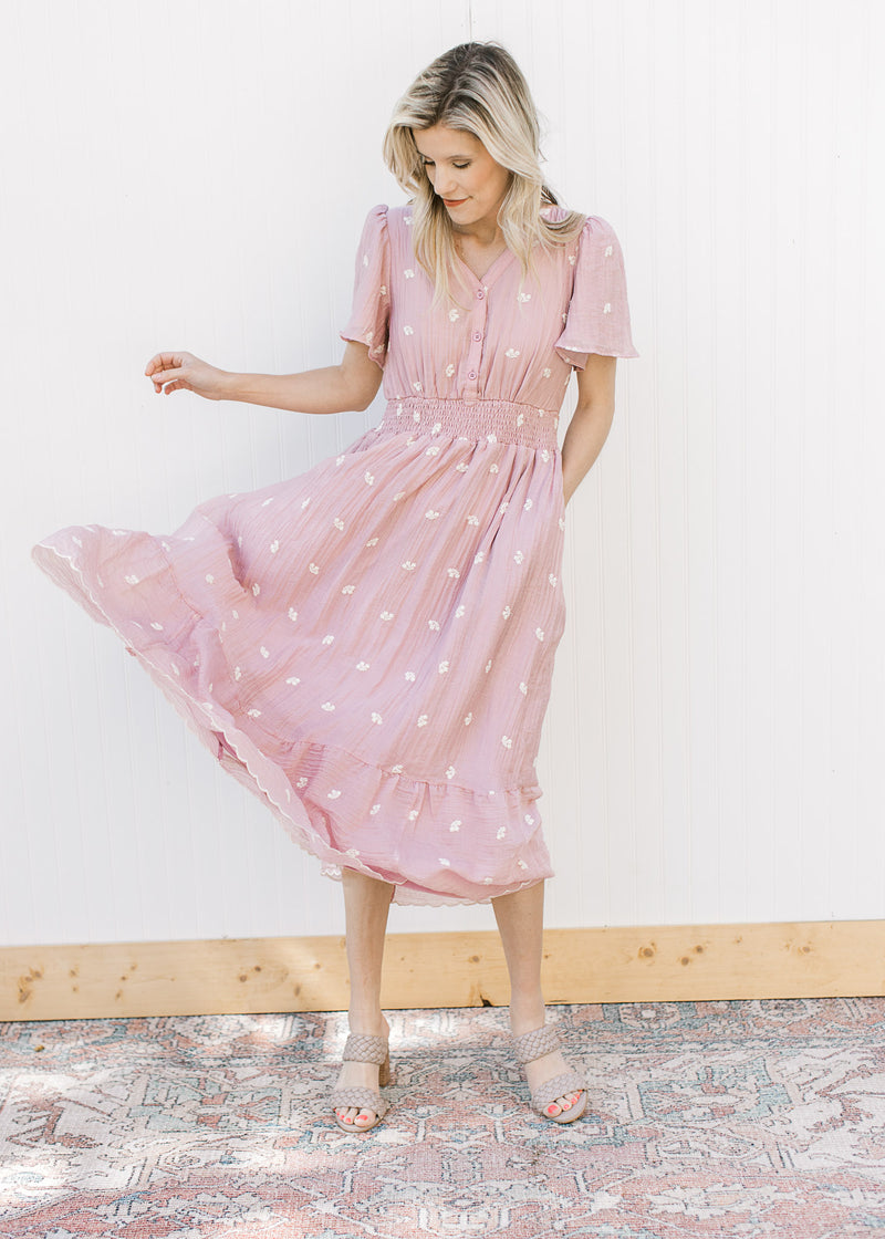 Model wearing a pink midi with short sleeves, three buttons and a flowy skirt. 