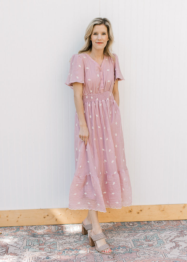 Model wearing a pink short sleeve midi with embroidered white flowers and a smocked waist.