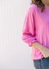 Close up of ruffle details and elastic cuff on a 3/4 sleeve of a bright pink top.