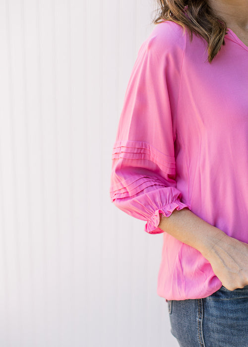 Close up of ruffle details and elastic cuff on a 3/4 sleeve of a bright pink top.