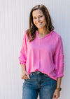 Model wearing a pink top with a v-neck, 3/4 sleeves and a rayon material. 