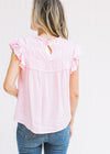 Back view of Model wearing a pink top with a smocked detail at bust, capped sleeve and keyhole. 