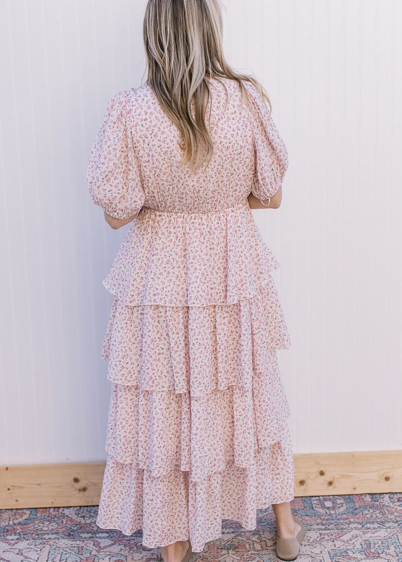 Back view of Model wearing a pale pink maxi with ditsy floral, ruffle tiers and bubble short sleeve.