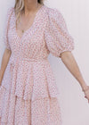 Close up of v-neck, bubble short sleeves and tie waist on a pale pink maxi with ditsy floral. 