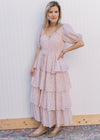 Model wearing a pale pink maxi with ditsy floral, tie at the waist, v-neck and bubble short sleeve.