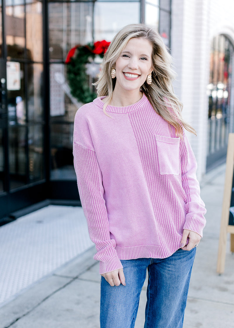 Model wearing a pink sweater with two styles of textured knit and a front patch pocket. 