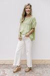 Model wearing white jeans, wedges and  a tiered top with balloon short sleeve and a keyhole.