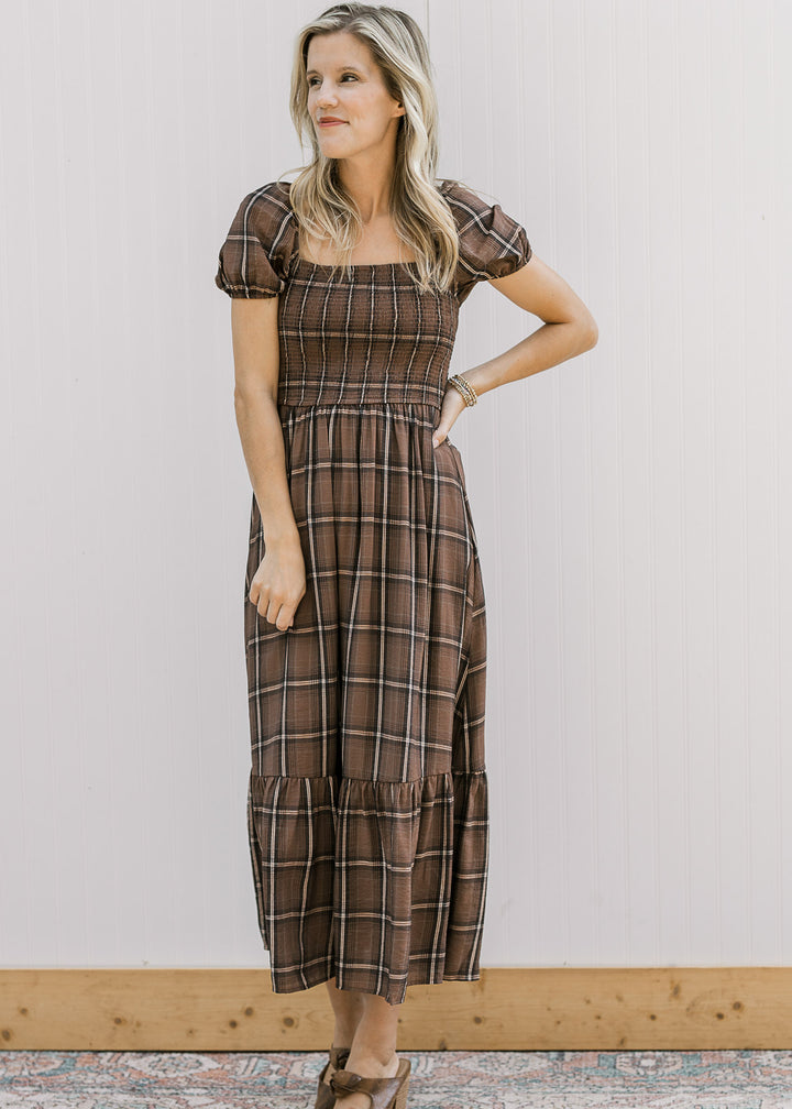 Model wearing a brown and cream plaid midi with a smocked bodice, short sleeves and full lining.