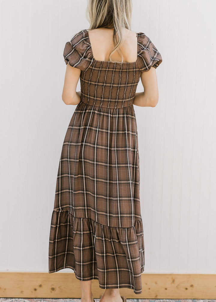 Back view of a brown and cream plaid midi with a smocked bodice, square neck and short sleeves. 