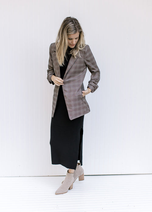 Model wearing a black maxi with booties and a brown plaid blazer with 3/4 tacked sleeves. 