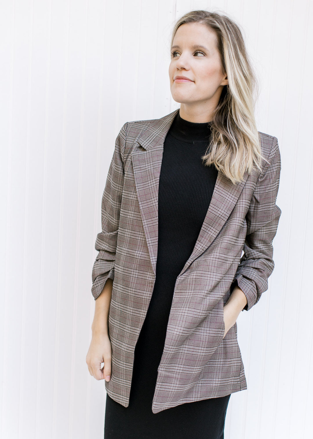 Model wearing a brown plaid blazer with 3/4 tacked sleeves and classic detailing. 