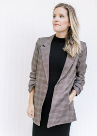 Model wearing a brown plaid blazer with 3/4 tacked sleeves and classic detailing. 