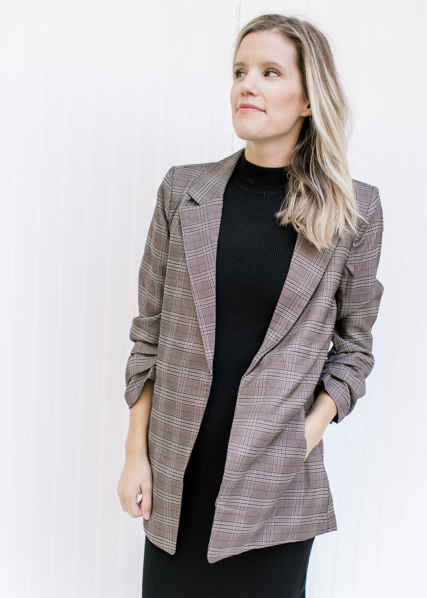 Model wearing a brown plaid blazer with 3/4 tacked sleeves and classic detailing. 