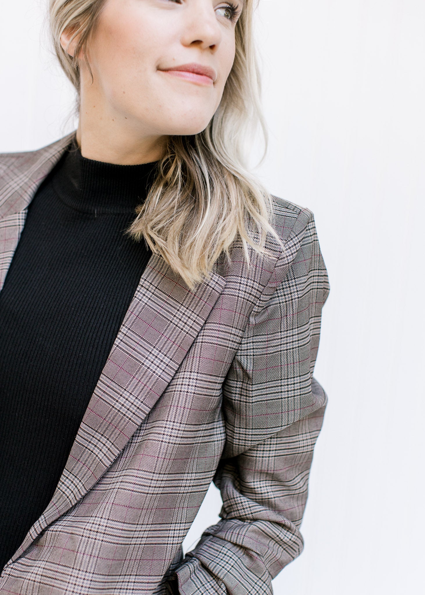 Close up of classic detailing on a Model wearing a brown plaid blazer with 3/4 tacked sleeves. 