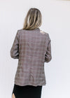 Back view of Model wearing a brown plaid blazer with 3/4 tacked sleeves and classic detailing. 