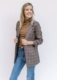 Model wearing jean with a black top and a brown plaid blazer with 3/4 tacked sleeves. 