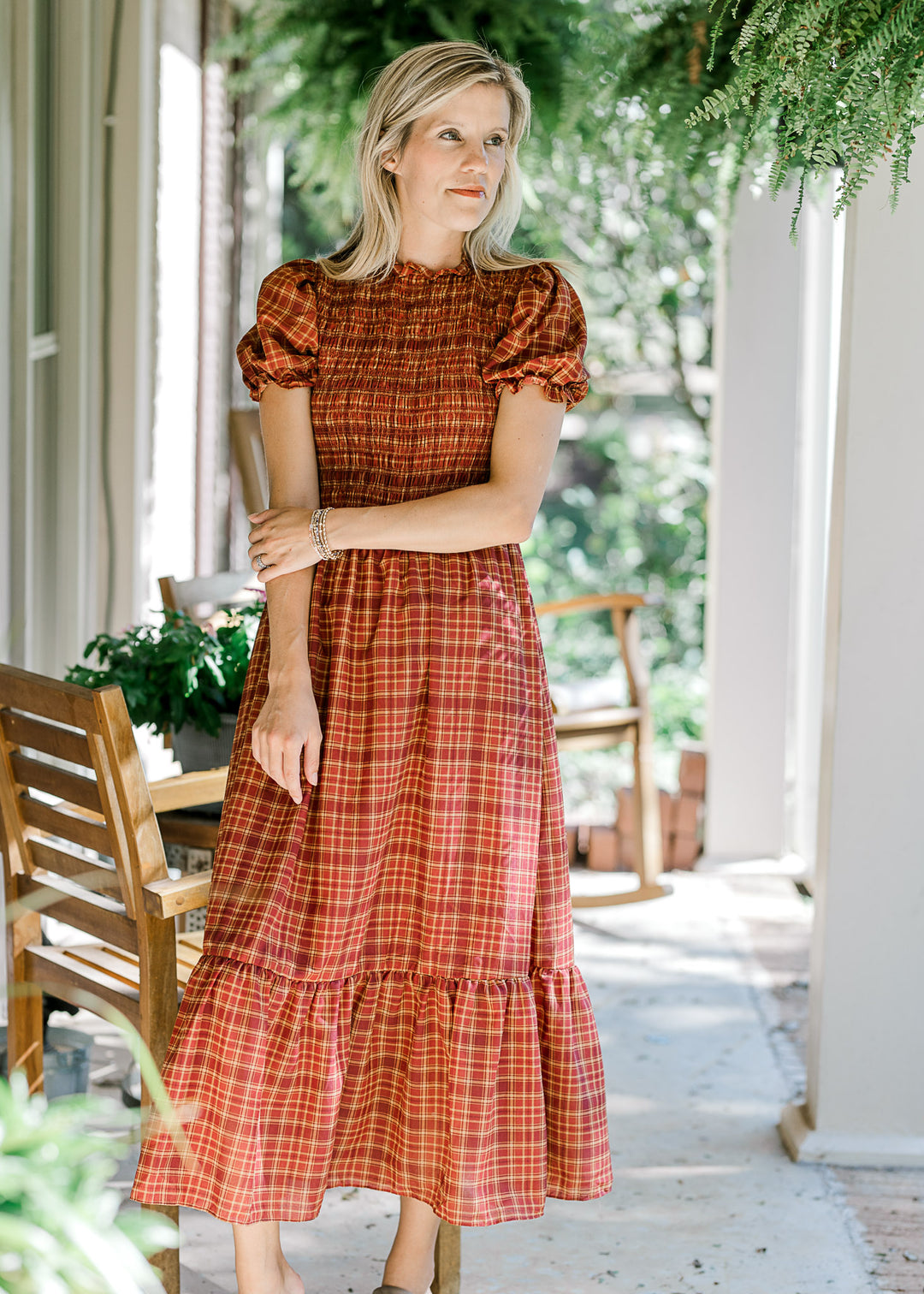 Model wearing a fall toned plaid midi with a smocked bodice and bubble short sleeves. 