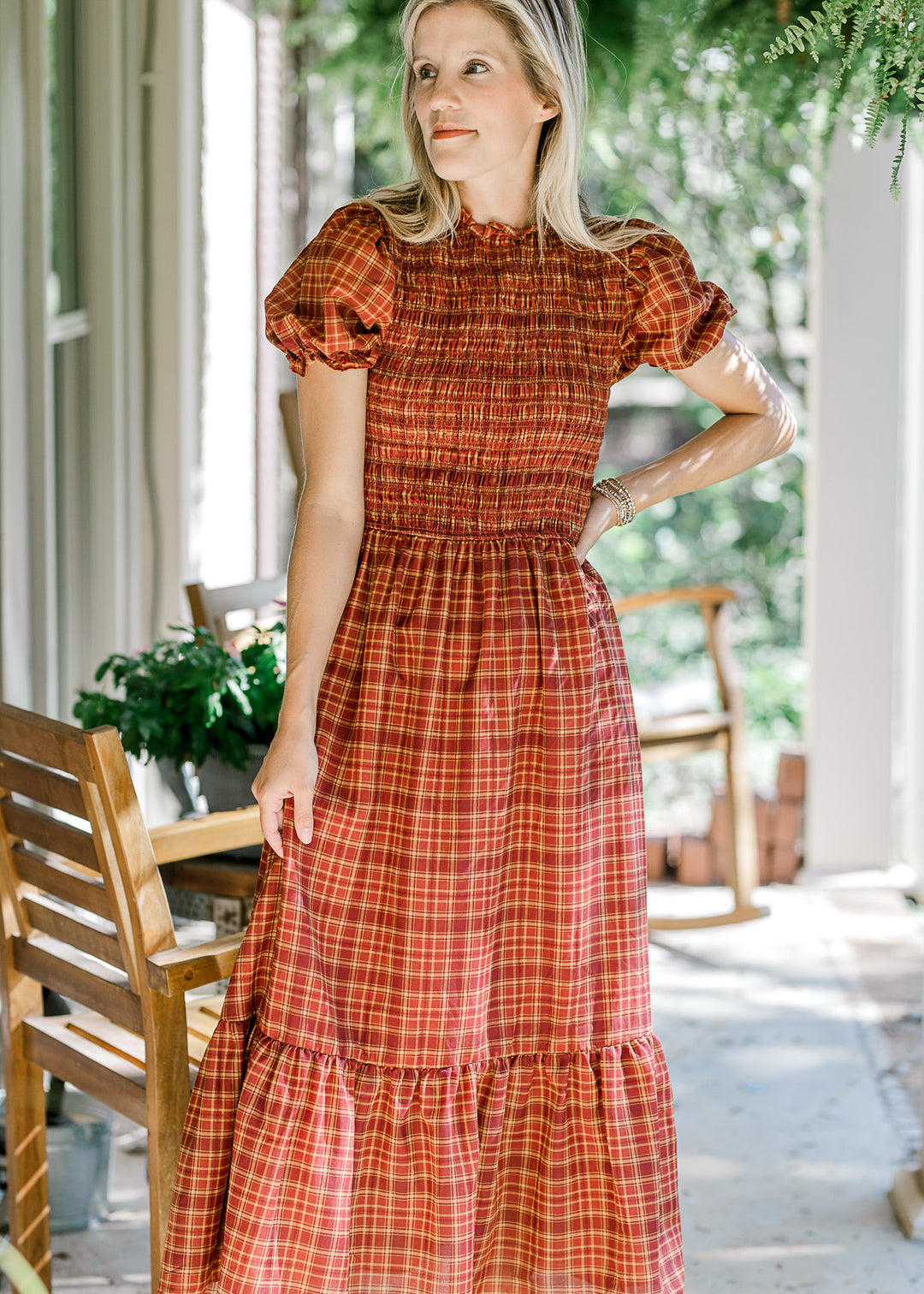 Model wearing a fall hued plaid midi with a smocked bodice, flowy skirt and bubble short sleeves. 