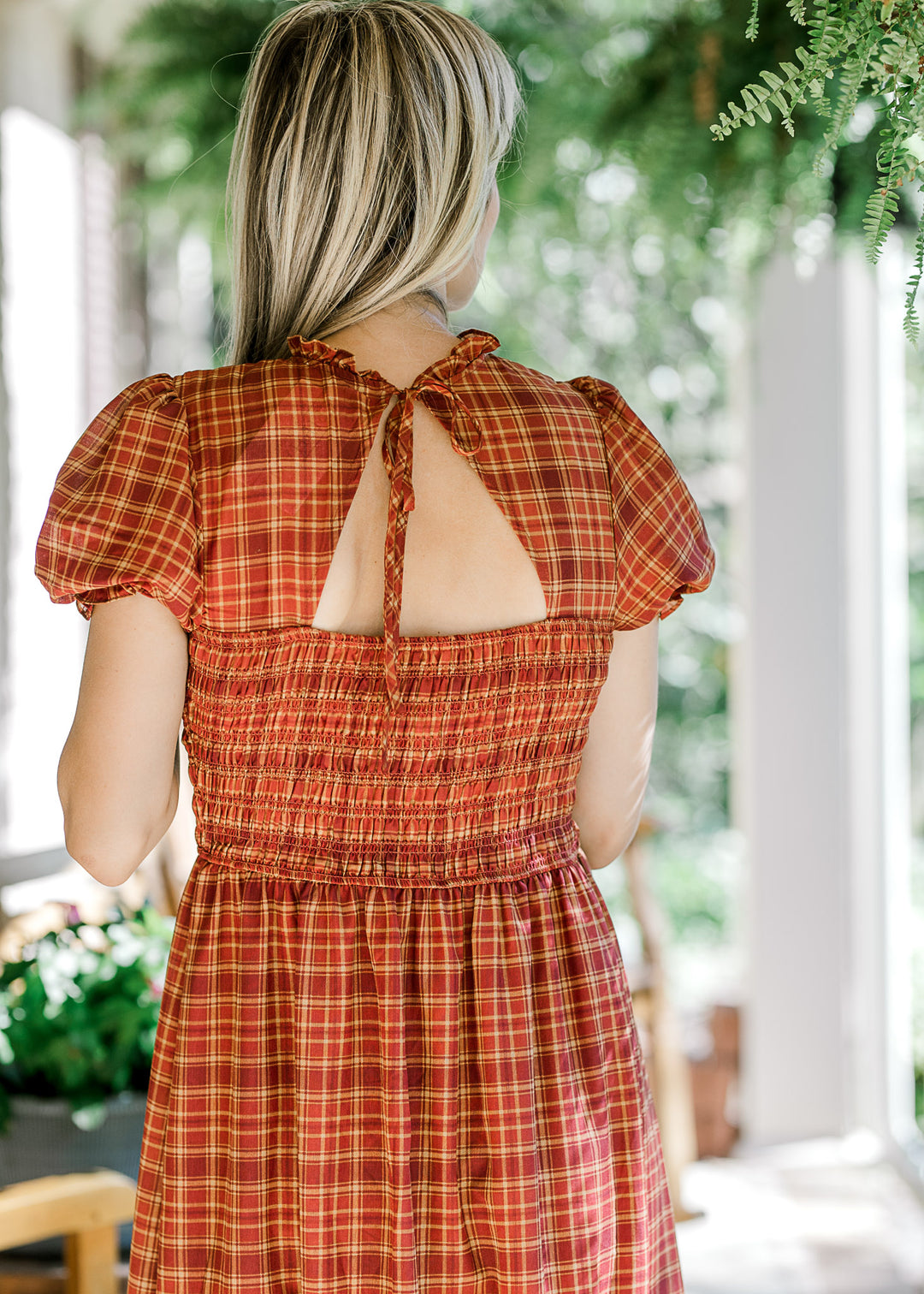 Back view of triangle cut out and tie on a fall hued midi with smocked bodice and bubble sleeves.