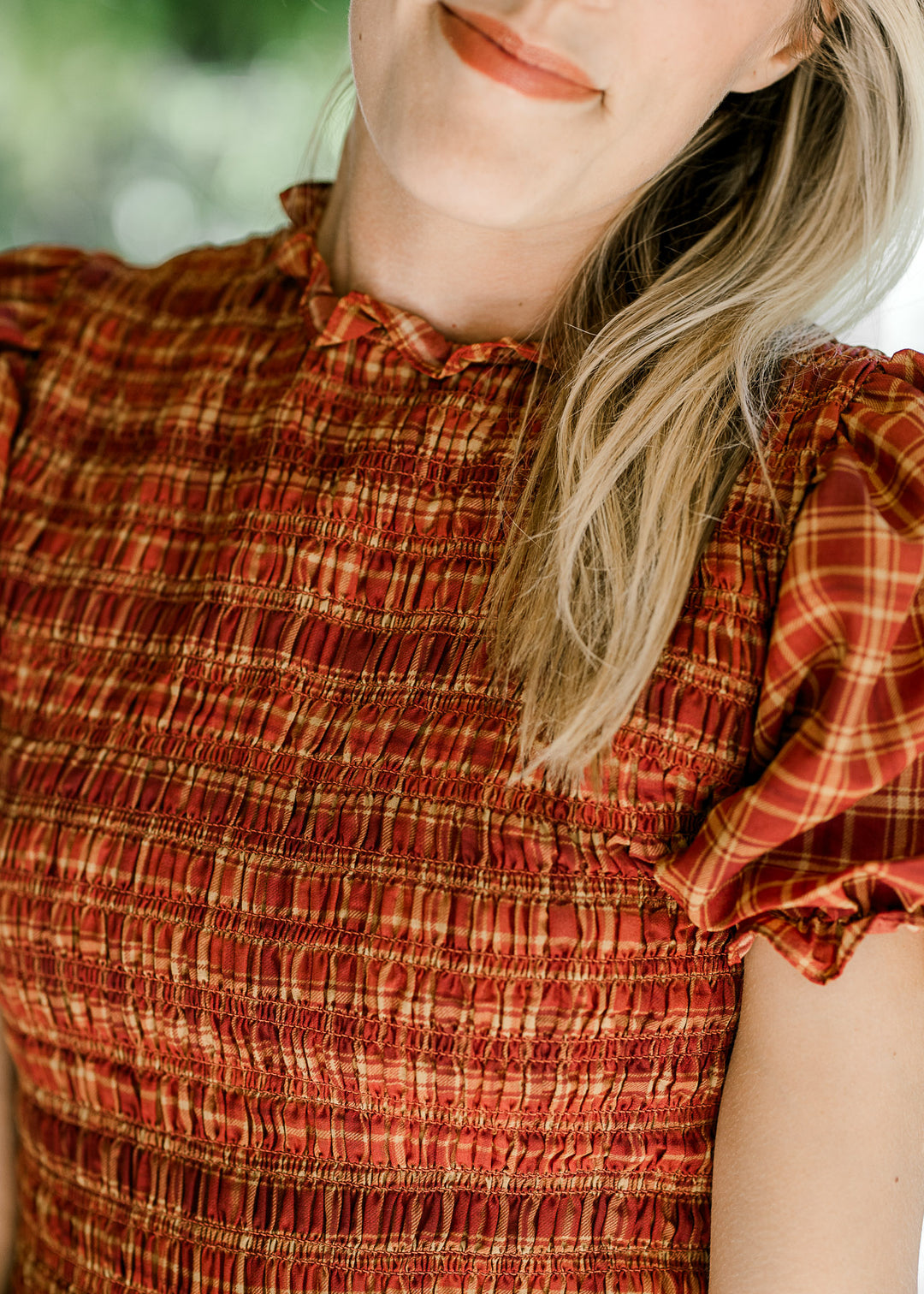 Close up of smocked bodice, bubble short sleeves and ruffle neck on a fall hued midi. 