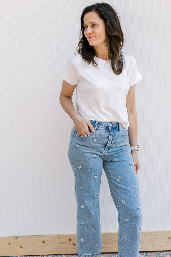 Model wearing a white, crew neck tee with an extended shoulder short sleeves and slightly cropped.