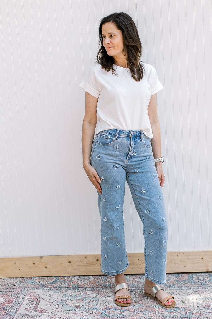 Model wearing jeans and a white, crew neck tee with short sleeves and a slightly cropped fit.