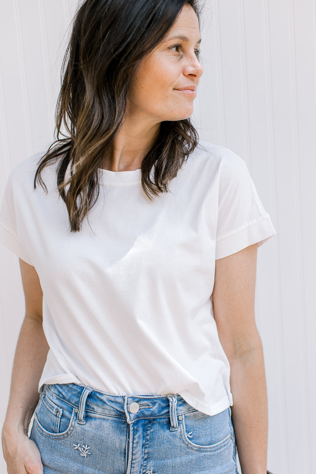 Model wearing a white tee with an extended shoulder short sleeves and a slightly cropped fit.